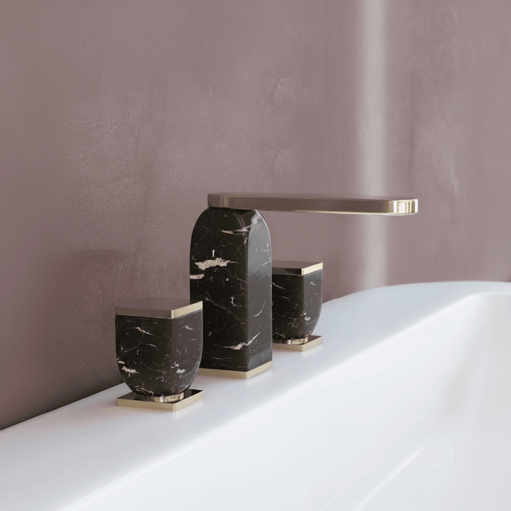 Three-hole deck-mounted basin mixer with sculpted black marquina marble body and champagne brass hardware, set against a warm dusty mulberry plaster wall