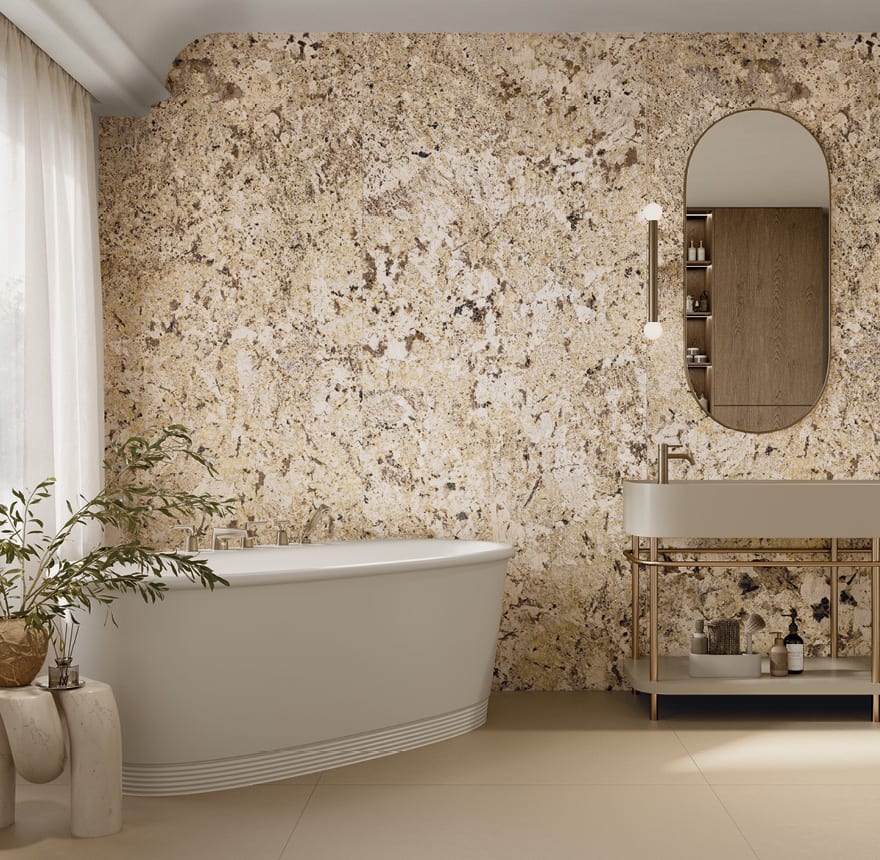 Granite-effect porcelain stoneware feature wall in warm cream and brown tones behind a freestanding bathtub